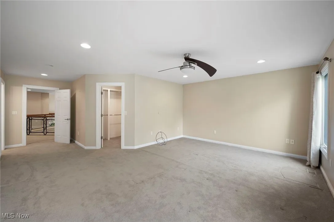 Unfurnished bedroom featuring light carpet, recessed lighting, a walk in closet, a ceiling fan, and a closet