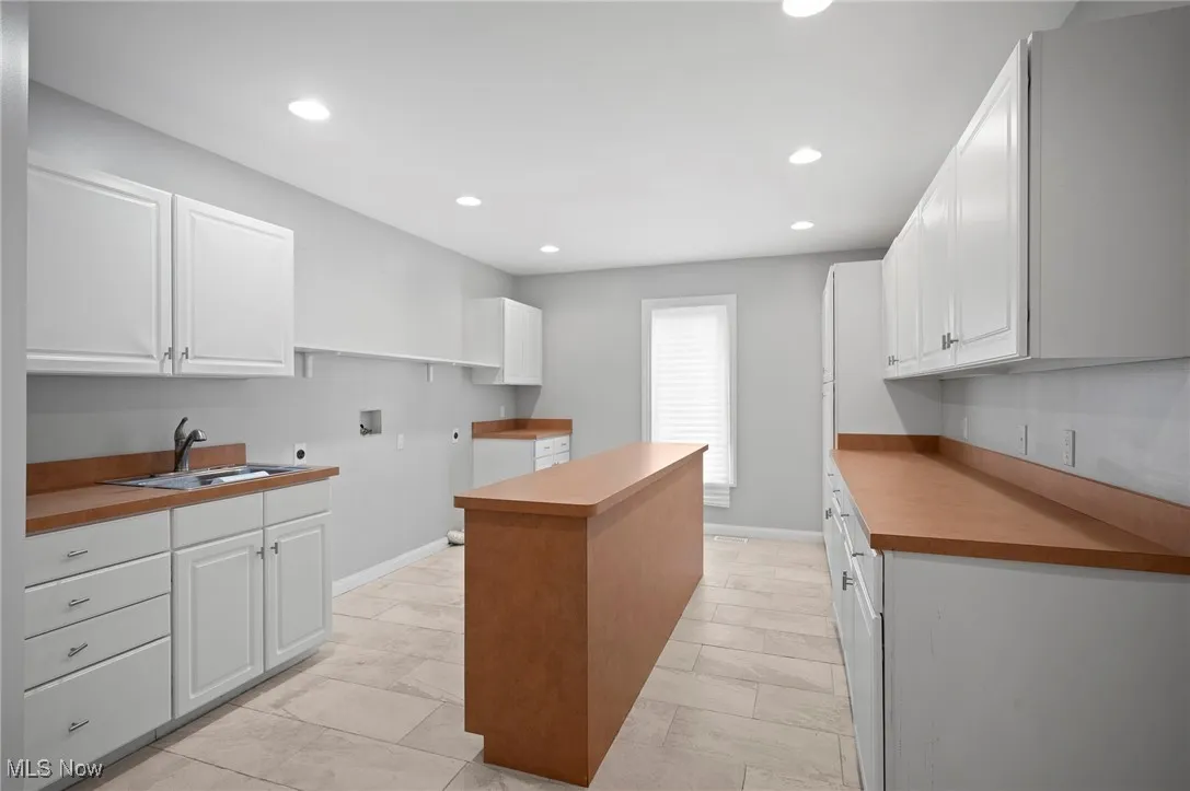Laundry Room with a center island, recessed lighting, and white cabinets