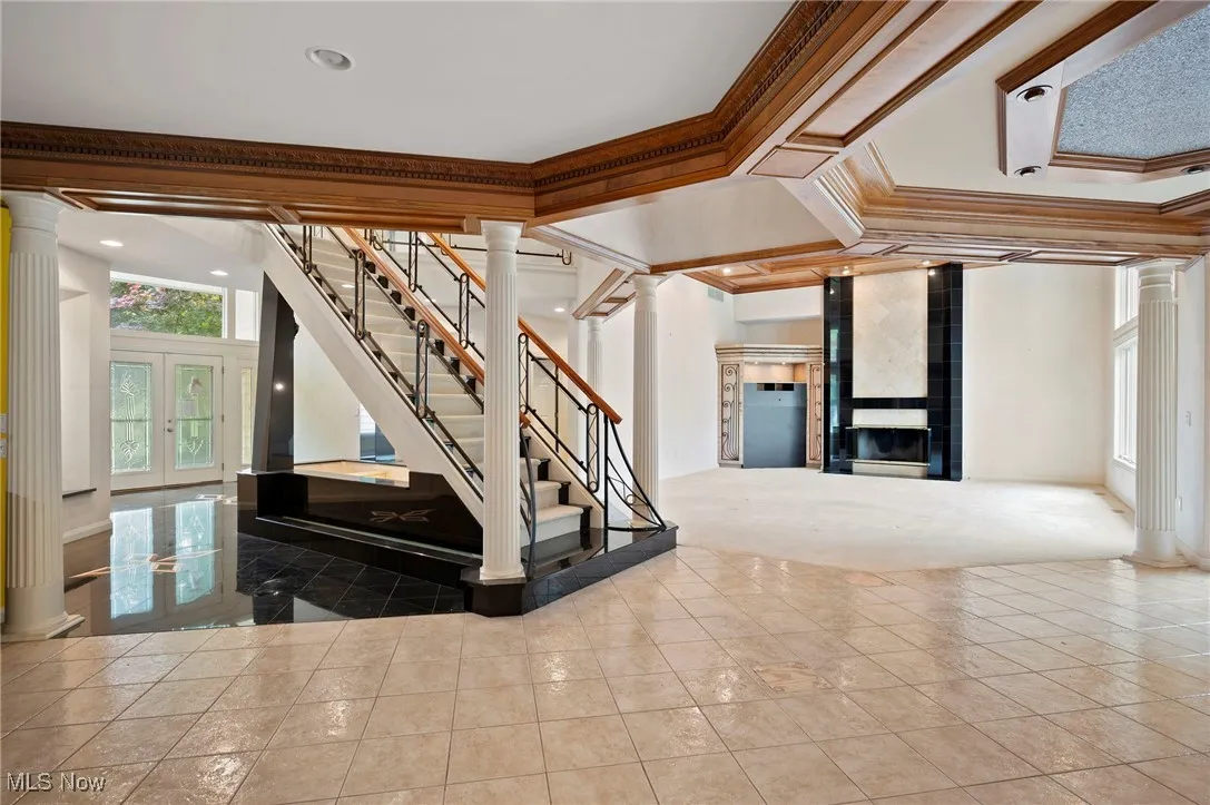 Stairs with decorative columns, crown molding, tile patterned floors, recessed lighting, and french doors