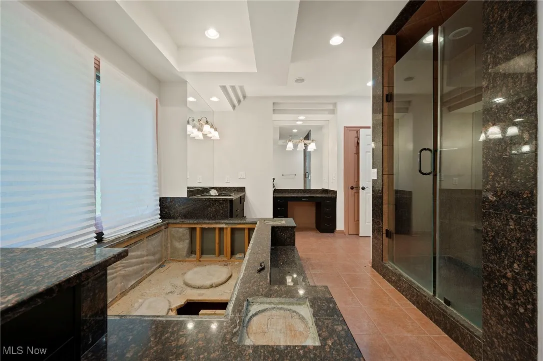 Bathroom featuring two vanities, a shower stall, tile patterned floors, a raised ceiling, and a bath