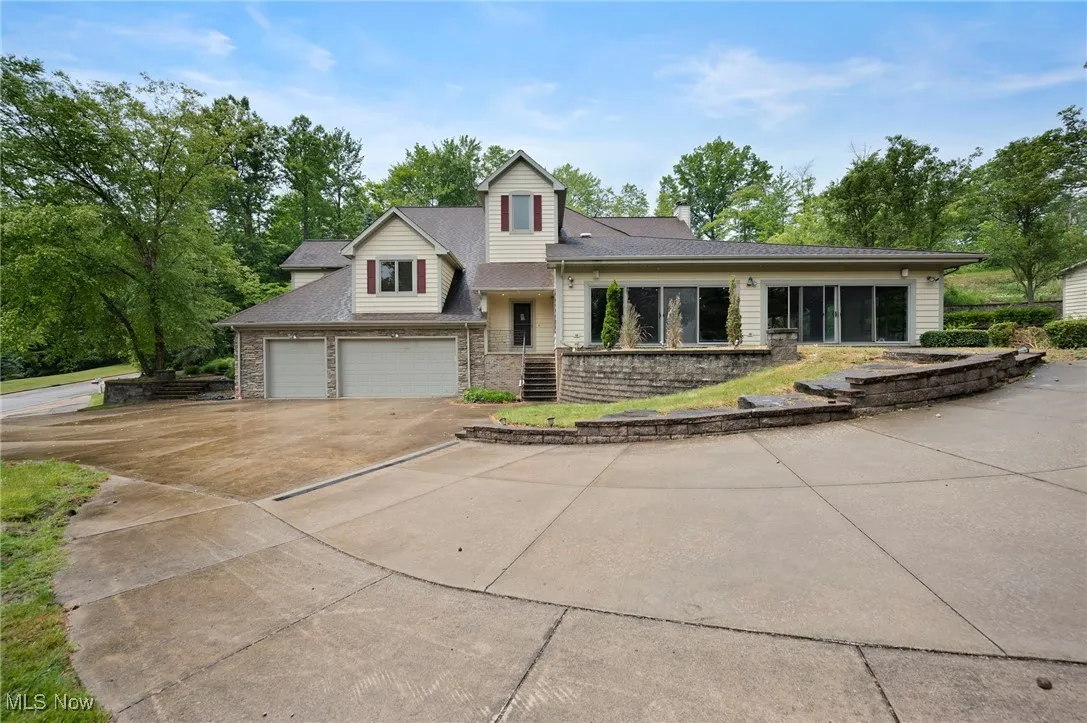 View of front of home featuring driveway, a chimney, stone siding, a garage, and roof with shingles