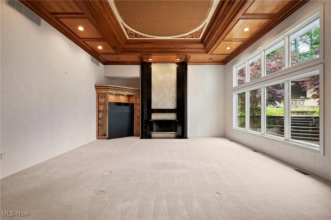 Unfurnished living room featuring crown molding, healthy amount of natural light, carpet flooring, a fireplace, and recessed lighting