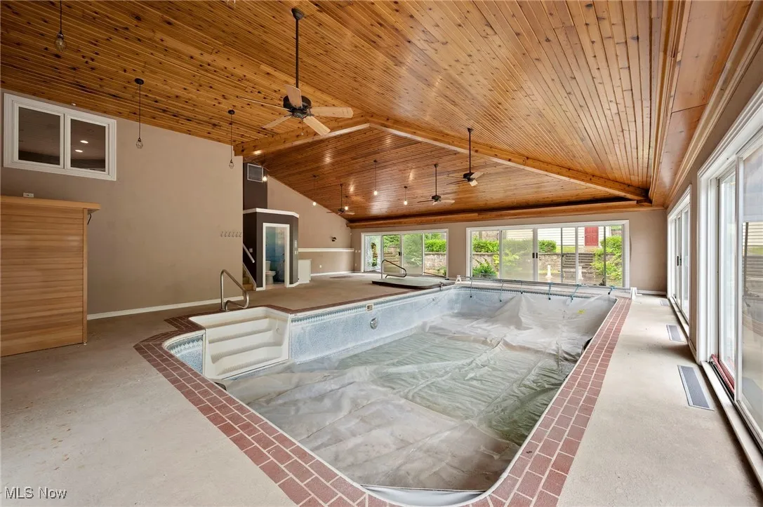 View of swimming pool with a hot tub, sauna, and ceiling fan