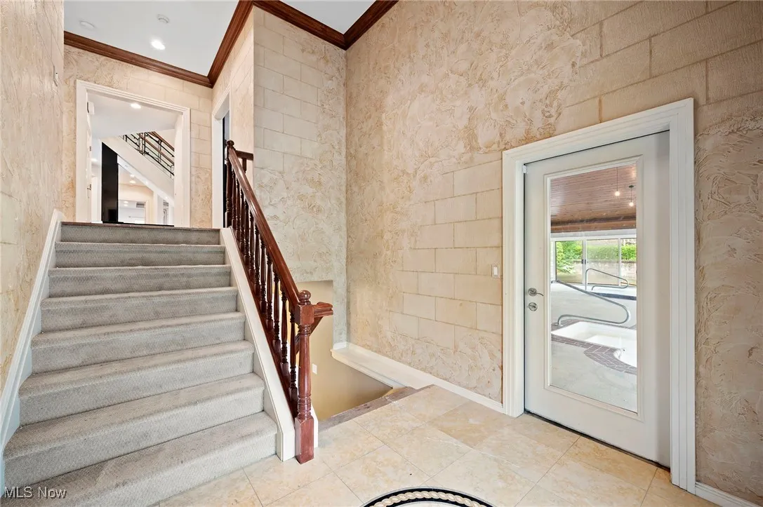 Entryway to the pool featuring ornamental molding, stairs, and wallpapered walls