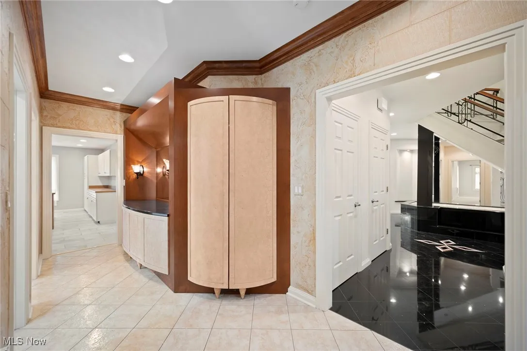 Hall to the pool with ornamental molding, wallpapered walls, stairway, and recessed lighting