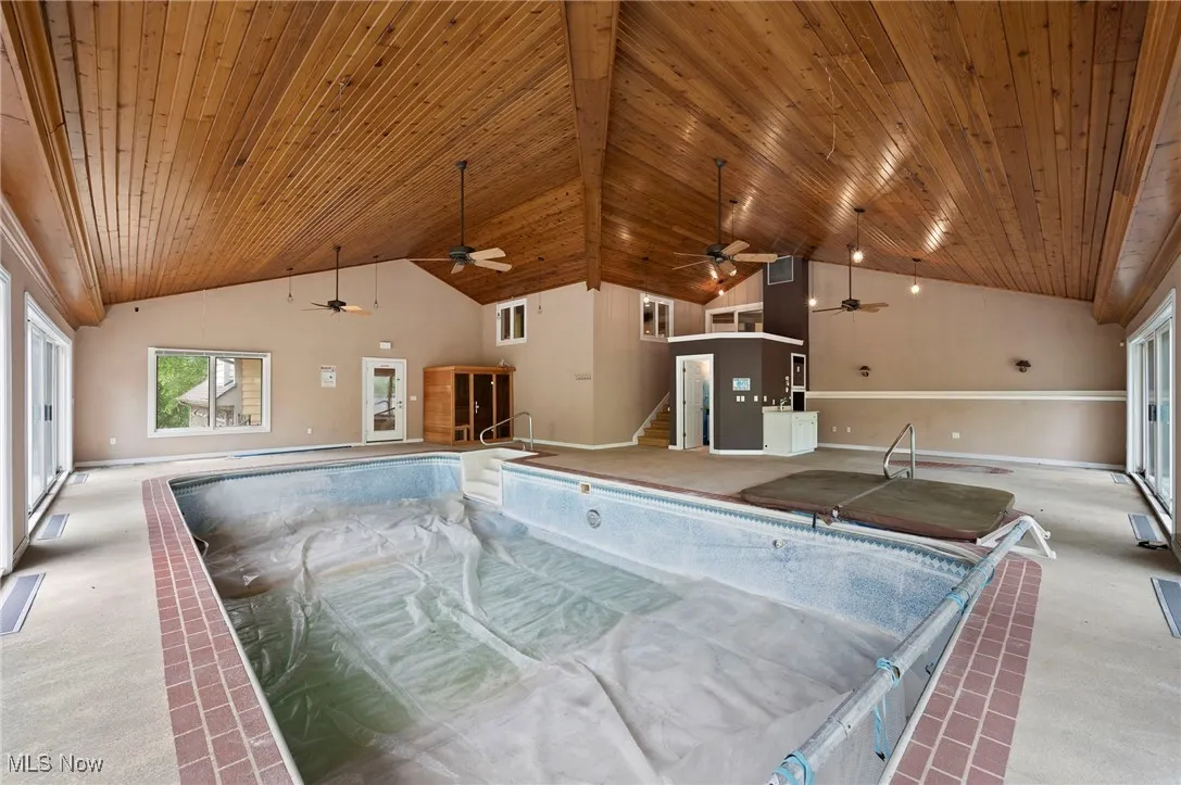 Indoor pool featuring a hot tub and ceiling fan