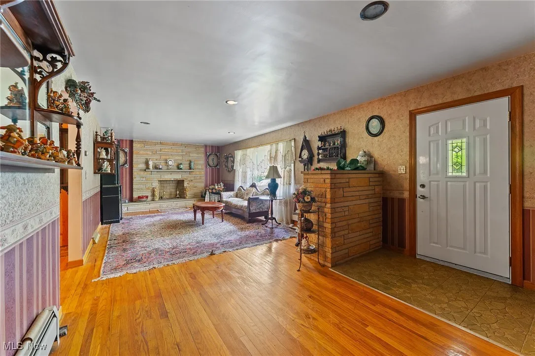Living room featuring a stone fireplace, wood finished floors, and recessed lighting