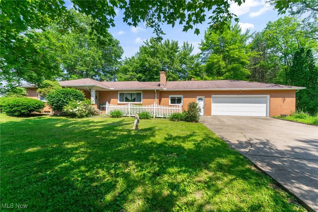 Ranch-style house with brick siding, a garage, a chimney, concrete driveway, and a front yard
