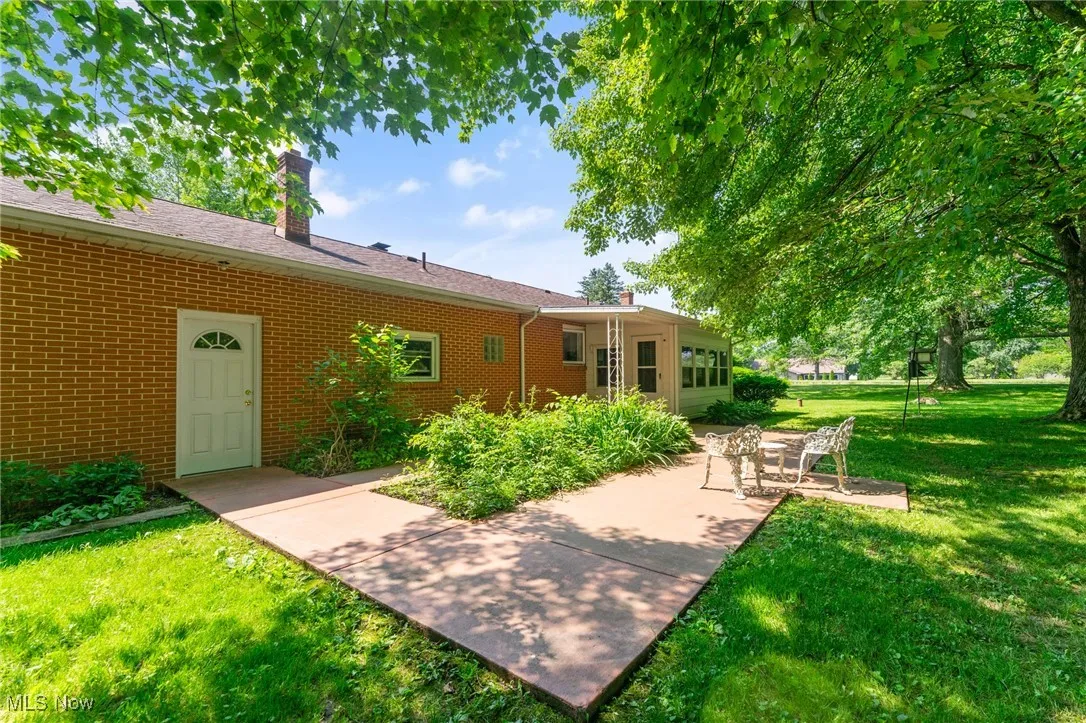View of green lawn featuring a patio area and sunroom.