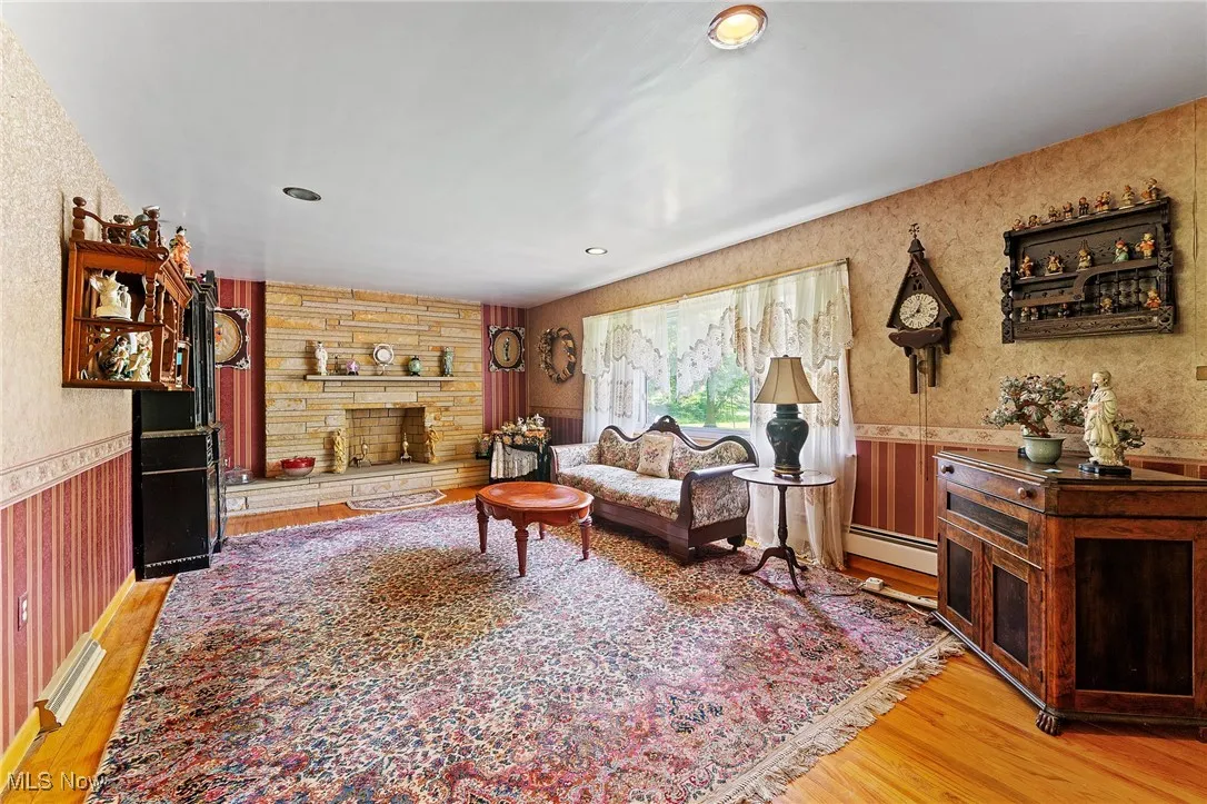 Living room featuring wallpapered walls, wainscoting, light wood-style floors, a stone fireplace, and recessed lighting