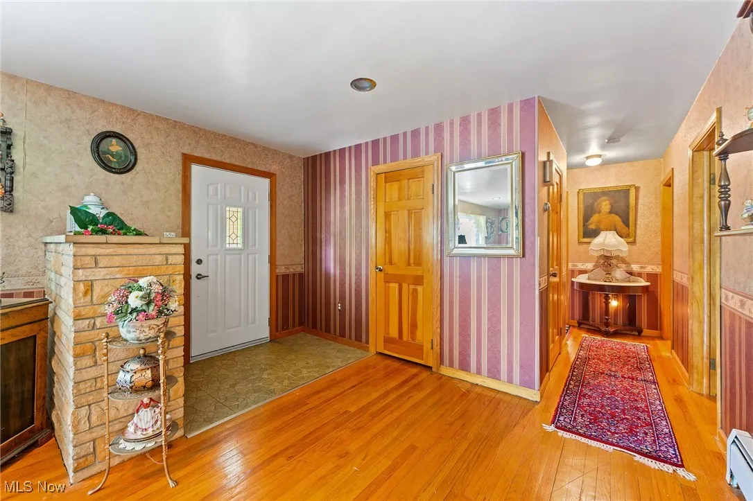 Foyer featuring wallpapered walls, hardwood floors.