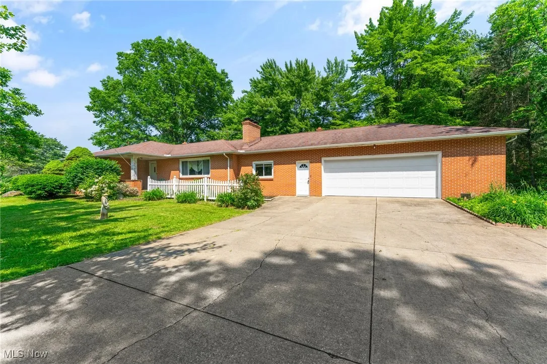 Ranch-style home featuring brick siding, covered porch, a garage, concrete driveway, and a front yard