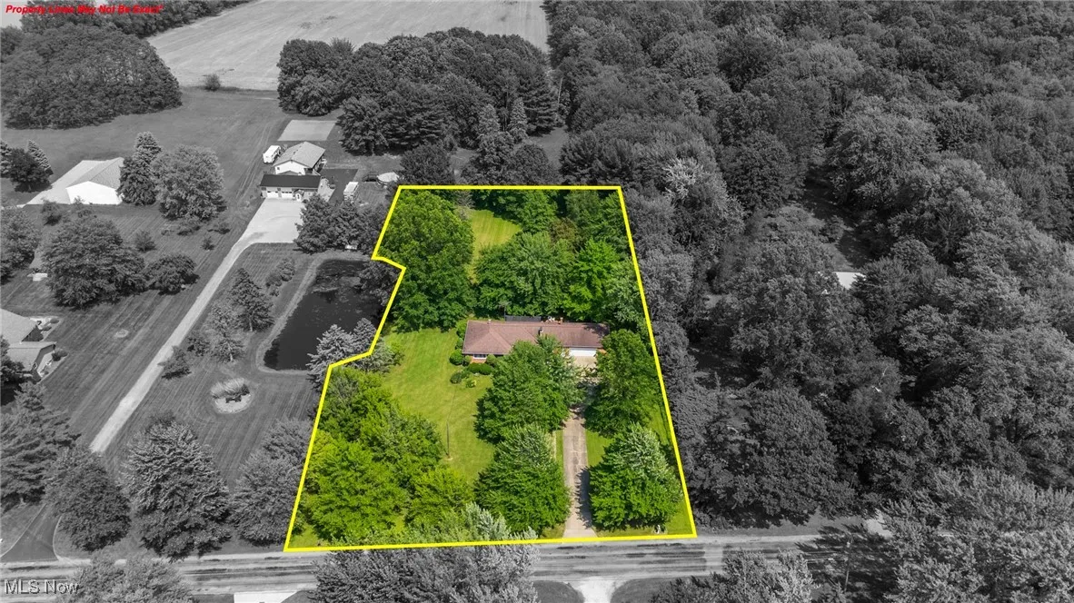 Aerial view of property and surrounding area with a heavily wooded area and property parcel outlined