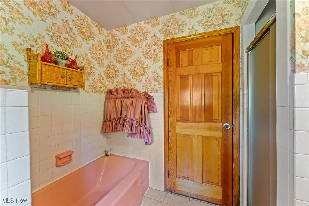 Full bath featuring wallpapered walls, a bathtub, tile patterned flooring.