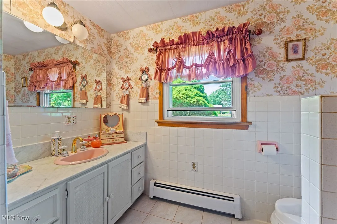 Bathroom with a nice vanity, tile walls, tile patterned flooring, and healthy amount of natural light