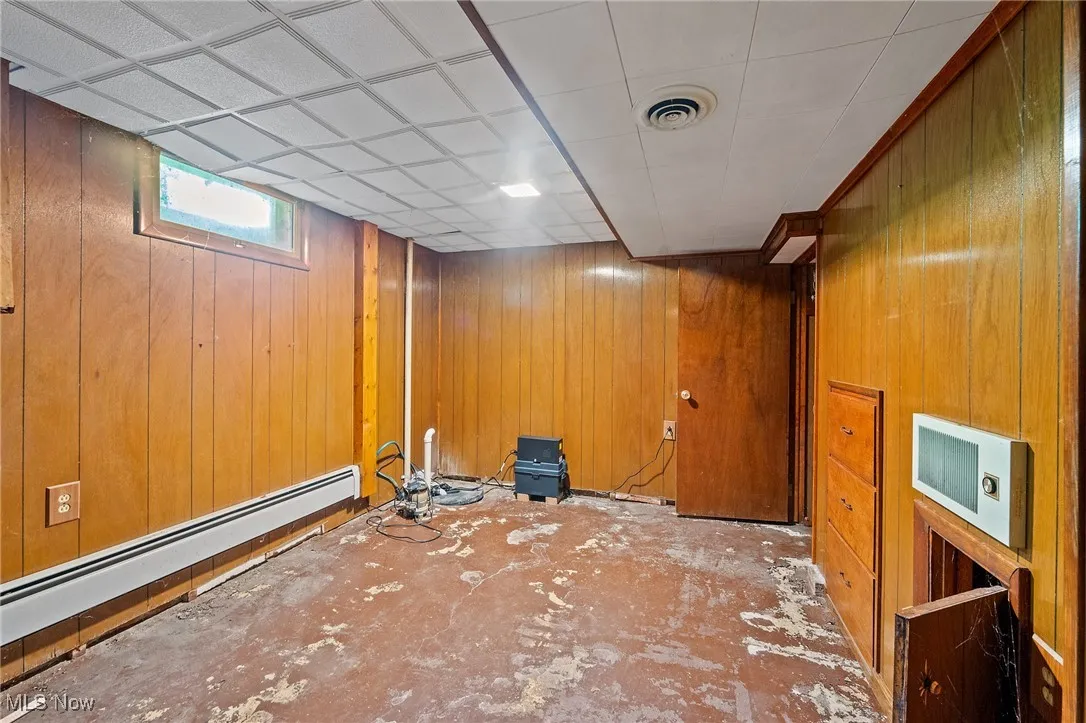 Basement featuring wooden walls and baseboard heating