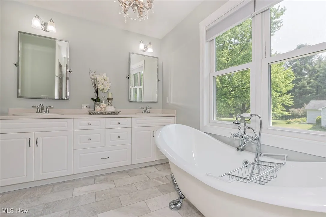 Luxe bath with soaking claw foot bathtub, dual vanity sink, marble tile, and walk-in shower.