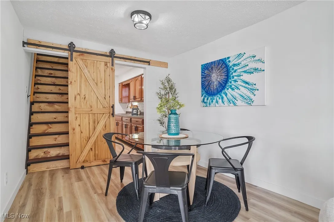 Dining space with a barn door, light wood finished floors, and a textured ceiling