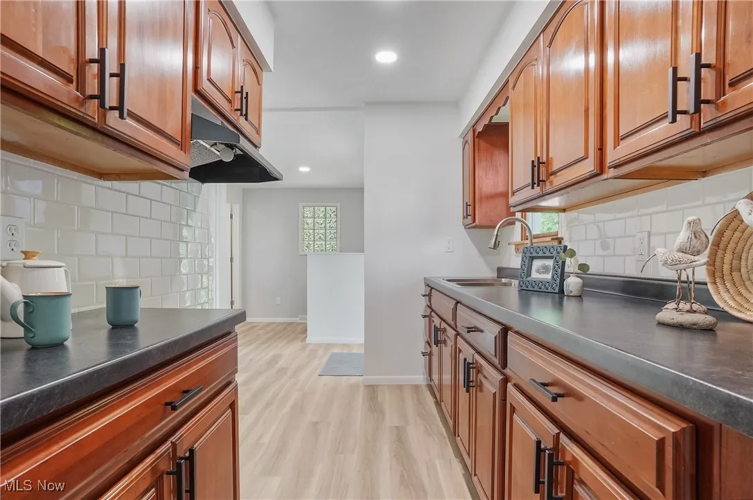 Kitchen featuring dark countertops, backsplash, brown cabinetry, and recessed lighting