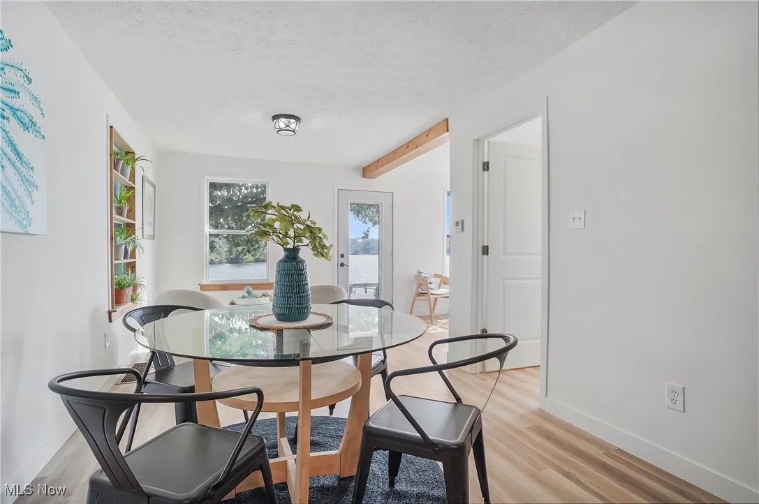 Dining space featuring a textured ceiling, light wood-style floors, and beamed ceiling