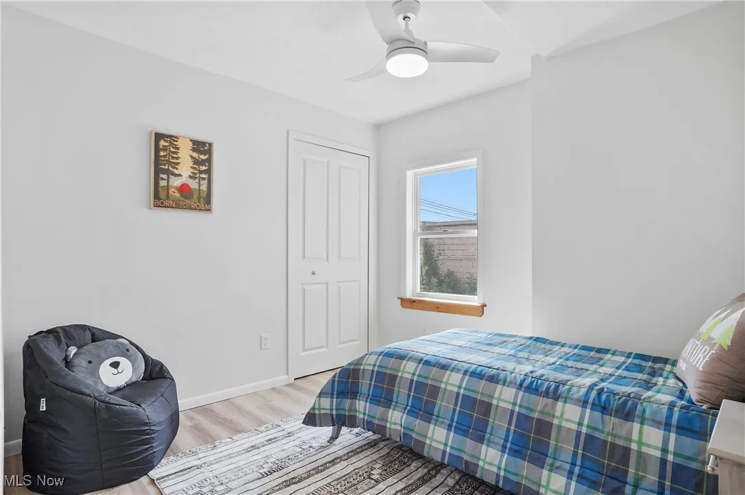 Bedroom with light wood-type flooring, ceiling fan, and a closet