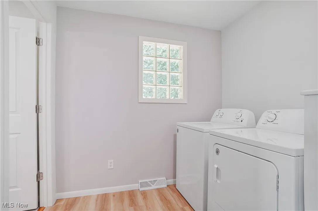 Laundry area with washing machine and clothes dryer and light wood finished floors