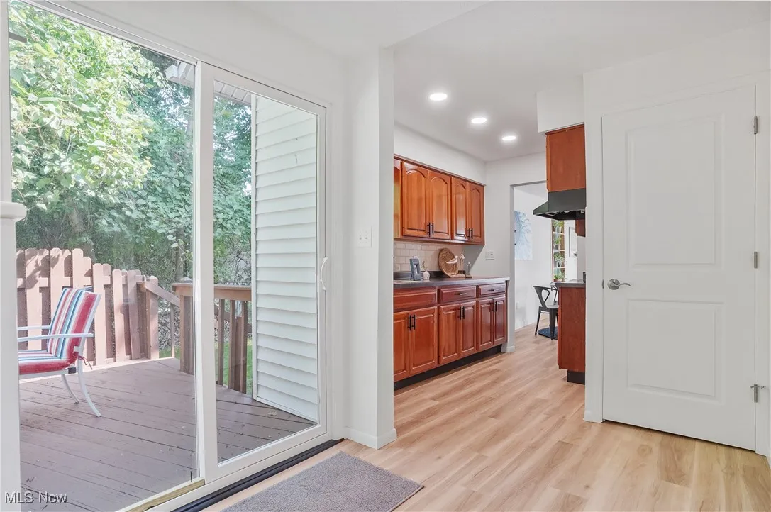Kitchen featuring light wood-type flooring, decorative backsplash, recessed lighting, brown cabinetry, and dark countertops