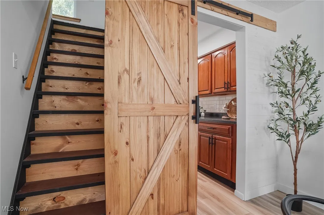 Stairway with a barn door and wood finished floors