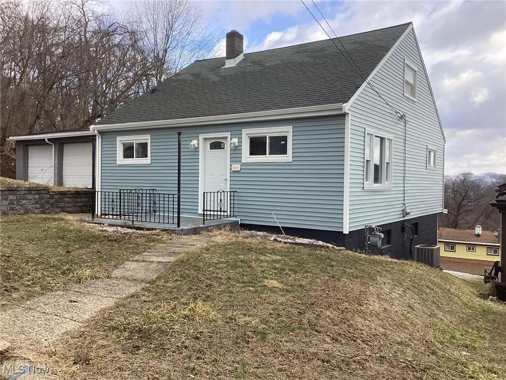 Rear view of property featuring a chimney, a yard, and roof with shingles