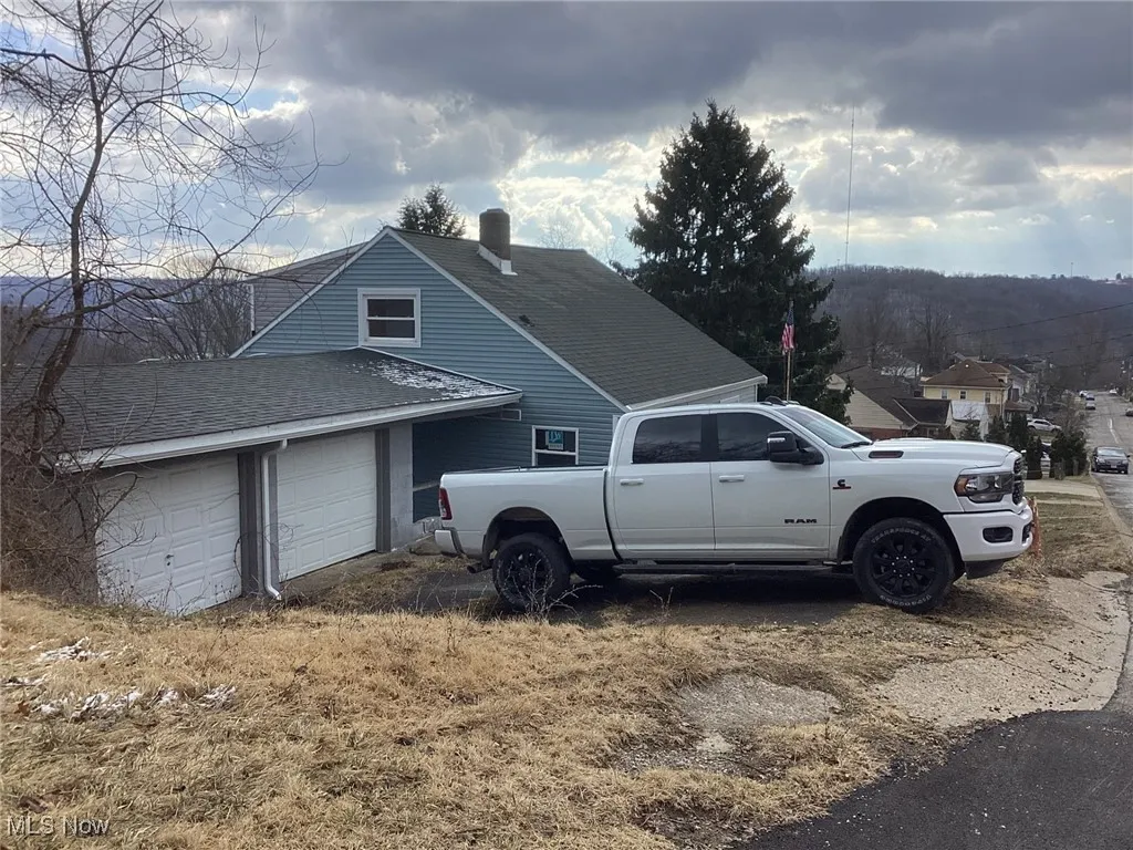 View of side of property featuring a shingled roof and an attached garage
