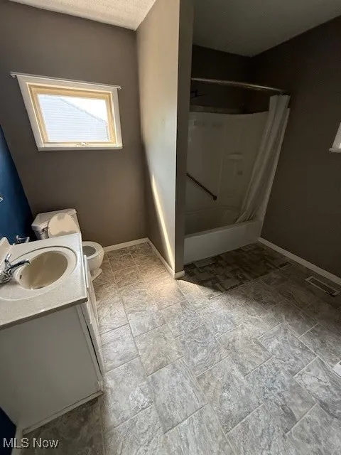 Full bath featuring a shower, vanity, and stone finish floors