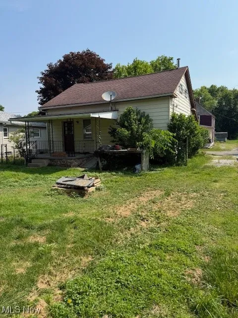 Back of house with a yard, a porch, and roof with shingles