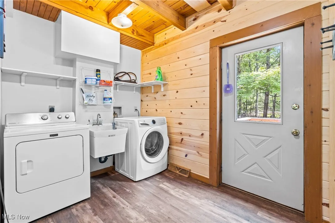 Laundry area with wood ceiling, separate washer and dryer, wood finished floors, wood walls, and a barn door