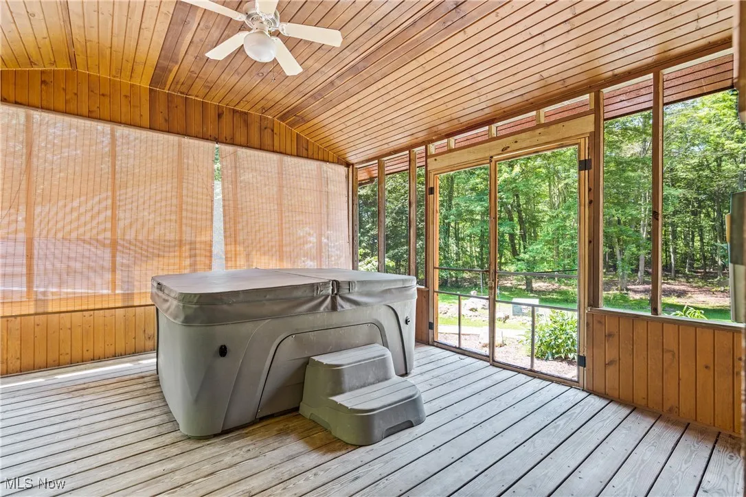 Unfurnished sunroom with lofted ceiling, a jacuzzi, and a ceiling fan