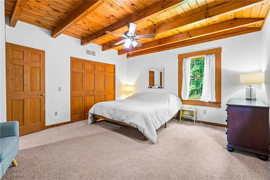 Bedroom with a wood ceiling with exposed beams, carpet flooring, a closet, and ceiling fan