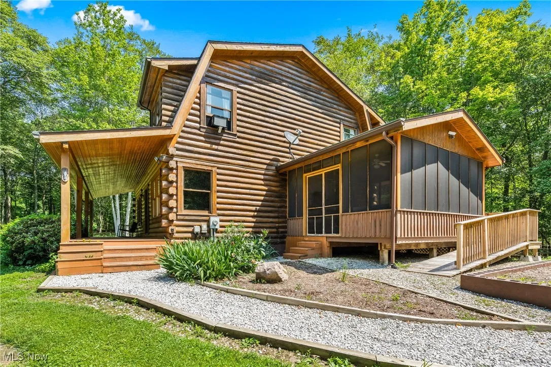 Back of property featuring a sunroom and log siding
