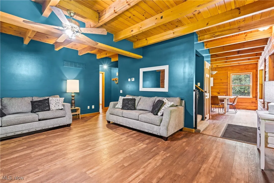 Living room featuring a wooden ceiling with exposed beams, wood finished floors, and ceiling fan