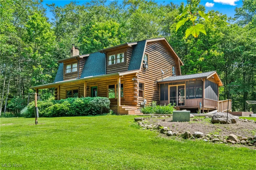 Log cabin with a sunroom, a chimney, a front lawn, log siding, and covered porch