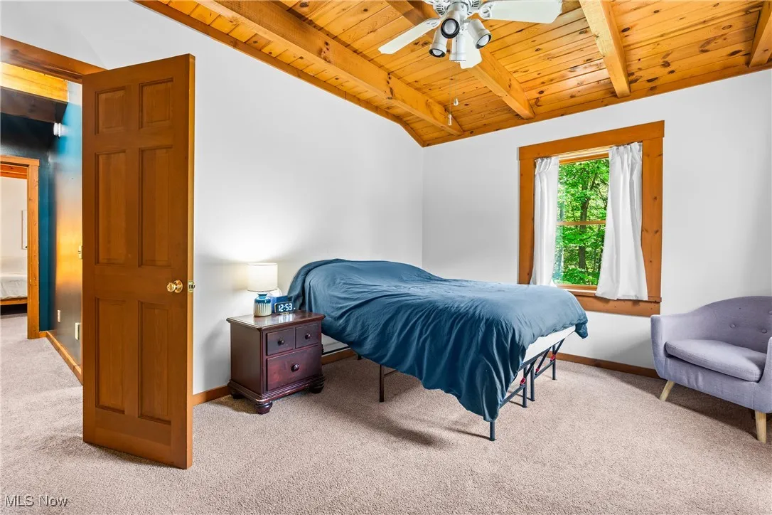 Bedroom with wooden ceiling, light carpet, and ceiling fan