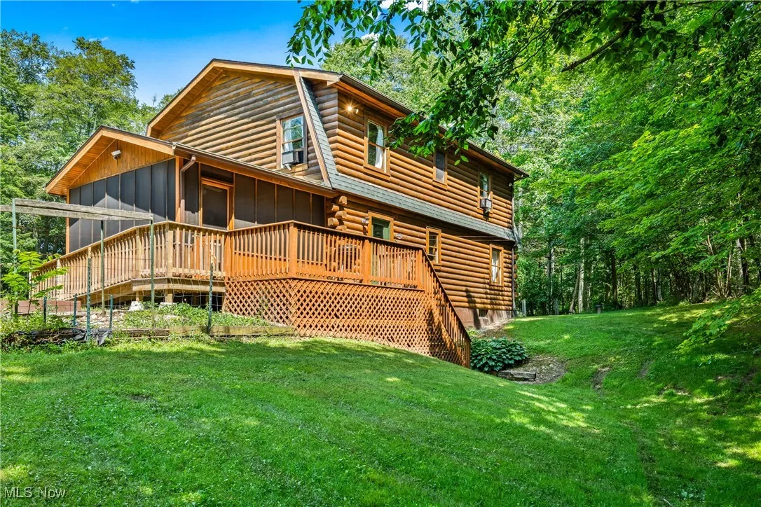 Rear view of property with log exterior, a lawn, stairs, a deck, and a sunroom