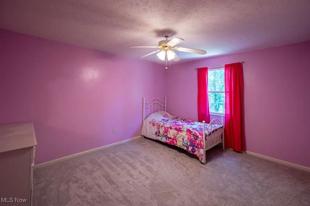 Carpeted bedroom featuring a textured ceiling and ceiling fan