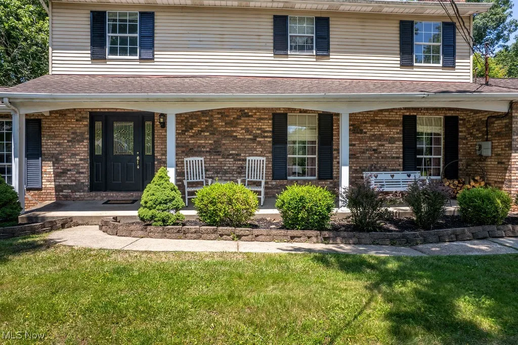 View of front of property featuring covered porch, a front lawn, and brick siding