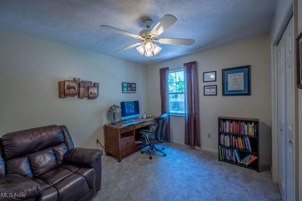 Office with carpet flooring, a ceiling fan, and a textured ceiling