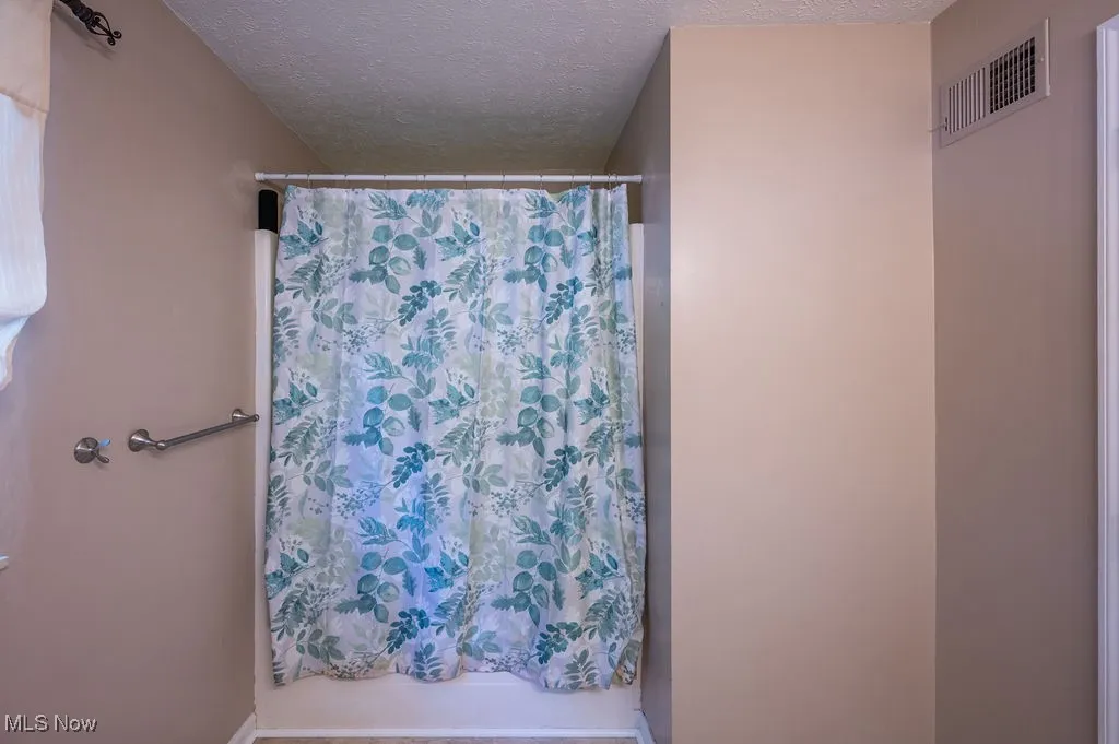 Full bathroom featuring curtained shower and a textured ceiling