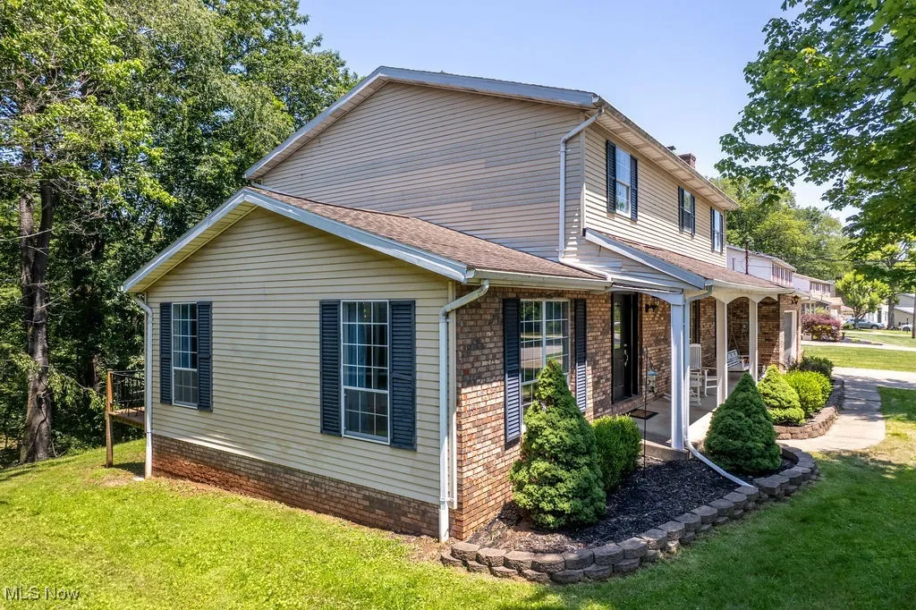 View of property exterior featuring a yard, a porch, and a chimney