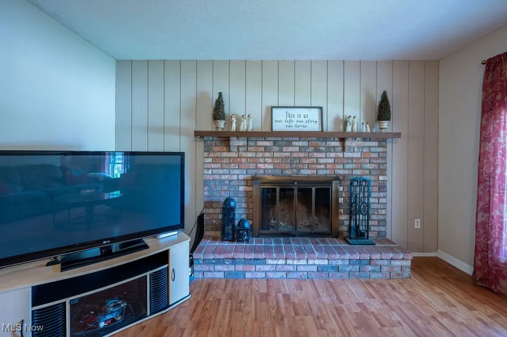 Unfurnished living room featuring wood finished floors, a fireplace, and a textured ceiling