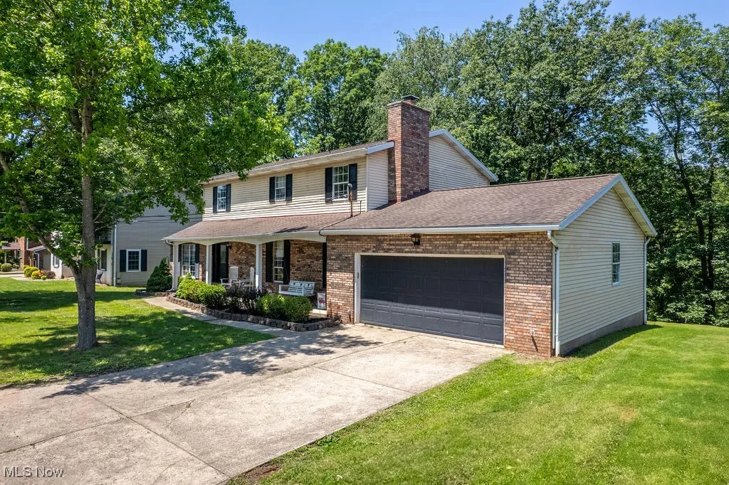 Traditional-style home featuring a porch, a garage, brick siding, and a front yard