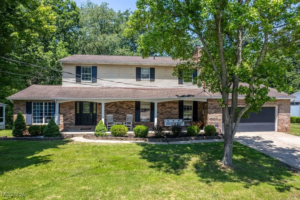 Traditional home with concrete driveway, a front yard, and brick siding