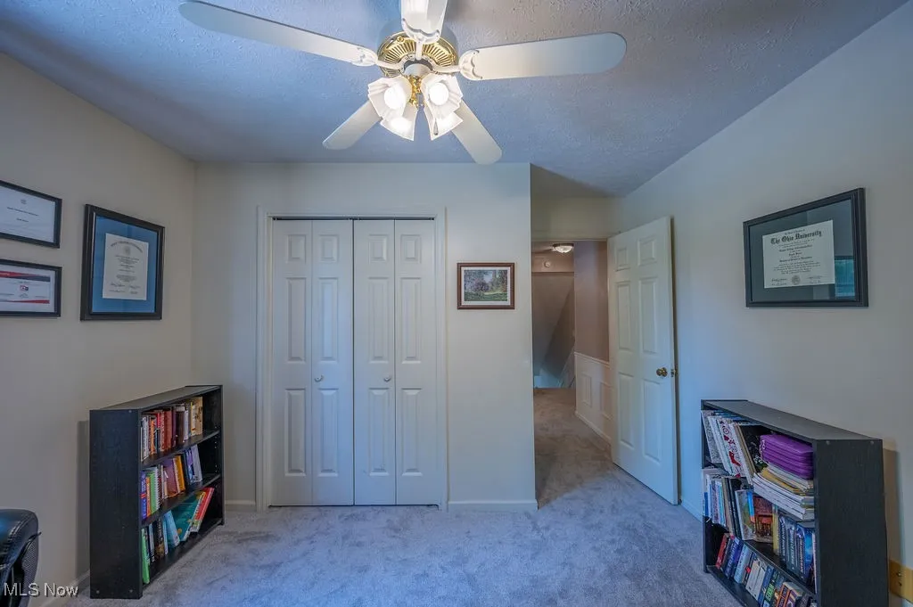 Carpeted bedroom with a textured ceiling, a closet, and ceiling fan