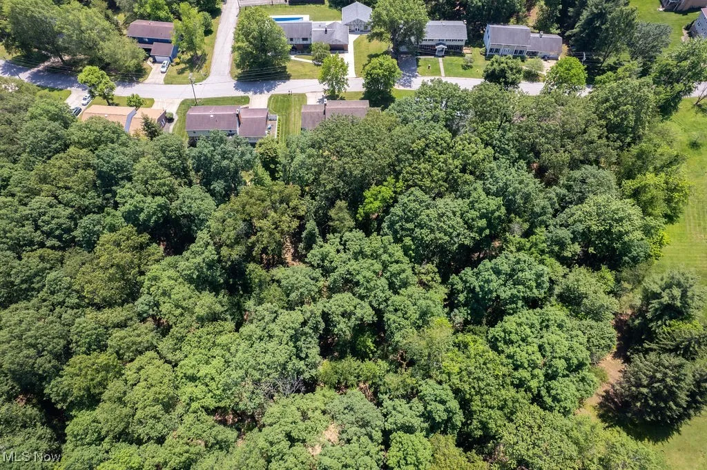 Aerial view of property and surrounding area with a heavily wooded area